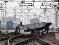 Gare de New Delhi, le 31 juillet, 2012, des livreurs indiens poussent un chariot au-dessus des voies ferrées près d’un poste électrique haute tension. (Roberto Schmidt/AFP/GettyImages)