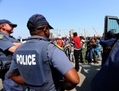 La police sud-africaine montent la garde pendant que les travailleurs en grève de l’Anglo American Platinum (Amplats) appellent leurs collègues lors du changement d’équipe à arrêter le travail à Rustenburg le 12 septembre. (Alexander Joe/AFP/GettyImages)