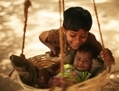 27 Mars 2010, Chandigarh, Inde, un garçon pose avec sa petite sœur qui se balance dans un panier suspendu . (Mark Kolbe/Getty Images)