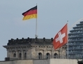 Les drapeaux suisses et allemands flottent au-dessus de l’ambassade de Suisse et de la Reichstag allemande en arrière plan, à Berlin. Après l’achat par les allemands de fichiers contenant les noms de leurs ressortissants fraudeurs du fisc, auprès des employés de banques Suisse, les deux pays ont adopté un traité fiscal bilatéral, qui reste à ratifier. (Sean Gallup/Getty Images)