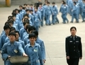 Des prisonniers passent à côté d’une escorte de policiers lors d’une journée portes ouvertes à la prison de Nanjing en Chine, 11 avril 2005. Les demandes pour l’abolition du système des camps de travaux forcés du régime chinois sont de plus en répandues en Chine. (STR/AFP/Getty Images)