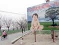 Le 25 mars 2001, une femme passe à vélo devant un panneau, installé sur la route vers  un village dans la banlieue de Pékin, encourageant les couples à n’avoir qu’un seul enfant. Un responsable du Parti a récemment proposé de passer à une politique de deux enfants dans certaines régions. (Goh Chai Hin/AFP/Getty Images)