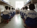 Des pratiquants de Falun Gong au camp de travail de Masanjia regardant une vidéo destinée à les rééduquer, au cours d’un cycle d’endoctrinement arrangé par les autorités du camp le 22 Mai 2001. L’une des tortures utilisées sur les pratiquants consiste à les menotter de manière très pénible entre des lits superposés, pour ensuite les séparer brutalement, causant une douleur atroce. (AP Photo/John Leicester)