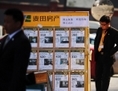 Le 1er avril 2013, à Pékin, un agent immobilier regarde un panneau de vente immobilière. La formation de la bulle du marché immobilier dans les grandes villes de Chine s’est ralentie suite aux nouvelles mesures d’assouplissement du Conseil d’Etat. (Wang Zhao/AFP/Getty Images)