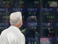 Un homme devant le tableau de cotation affichant la courbe du Nikkei, l’indice clé de la place financière japonaise, à Tokyo le 10 mai 2013. (Toru Yamanaka/AFP/Getty Images)