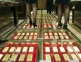 Le personnel chinois des équipes de ventes chemine sur une allée pavée de lingots d’or, d’une valeur estimée à plus de 100 millions de yuans (12.30 millions d’euros), dans une maison de change à Kunming, en Chine, le 11 décembre 2012. La Chine a importé une grande quantité d’or, mais au niveau mondial on ne connaît pas la quantité exacte détenue par le pays. (STR/AFP/Getty Images)