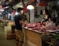 Sur cette photo prise le ler  juin 2013, un homme (à droite) regarde la viande dans une boutique de Pékin vendant du porc. Récemment, un abattoir à Pékin a été reconnu coupable d’avoir écoulé de la viande infectée vers des lycées, durant plus d’un an. (Wang Zhao/AFP/Getty Images)