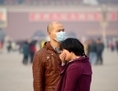 Place Tiananmen à Pékin le 5 novembre 2013, un homme (à gauche) porte un masque sur le visage tandis qu’une touriste recouvre sa bouche. Selon les conclusions du 6e Sommet chinois nord-sud portant sur le cancer du poumon et se déroulant à Pékin les 16 et 17 novembre, en raison des effets du tabac et de la pollution de l’air, le pays devrait atteindre le million de patients touchés par le cancer du poumon en 2025. (Wang Zhao/AFP/Getty Images)