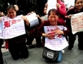 Le 13 mai 2010, un groupe de femmes pétitionnaires s’agenouillent en pleurant devant un tribunal de la municipalité de Chongqing (sud-ouest de la Chine). Elles tiennent des affiches en papier dénonçant les responsables du régime qui ont confisqué leurs terres et propriétés et enferment illégalement les pétitionnaires dans des prisons secrètes. (AFP/AFP/Getty Images)