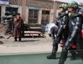 On voit des caractères chinois sur cette photo d’un Tibétain (gauche) en costume traditionnel regardant les troupes paramilitaires chinoises en tenue anti-émeute marcher dans les rues de Guomaying, sur le plateau tibétain. La politique chinoise semble vouloir remplacer les langues ethniques par le mandarin. (Frederic J. Brown/AFP/Getty Images)