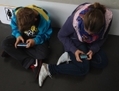 Deux enfants jouent à des jeux vidéo sur leurs téléphones. Le monde subit l’essor de l’utilisation du smartphone qui aura, à long terme, un impact certain sur les relations humaines. (Sean Gallup/Getty Images)
