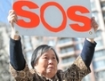 15 avril 2014: Huang Jinling déploie une banderole lors d’une conférence de presse à Calgary, Canada appelant à l’aide pour secourir sa fille Chen Yinghua. (Wu Weilin/Epoch Times) 