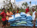 En avril 2014, des Philippins affectés par le typhon Haiyan reçoivent des sacs de riz avant la saison des semis. (Photo FAO)
