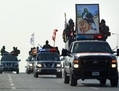 Des membres des forces spéciales de la police irakienne circulent en véhicules le 19 novembre 2014 à Najaf avant d’aller combattre l’État islamique. Sur l’un des véhicules se trouve un portrait de l’imam Hussein, une figure centrale de la religion musulmane chiite, renforçant ainsi l’image d’un conflit de nature sectaire. (Haidar Hamdani/AFP/Getty Images)  