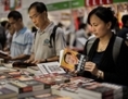 Des visiteurs feuillettent des livres politiques au Salon du livre de Hong Kong le 18 juillet 2012. (Philippe Lopez/AFP/GettyImages) 
