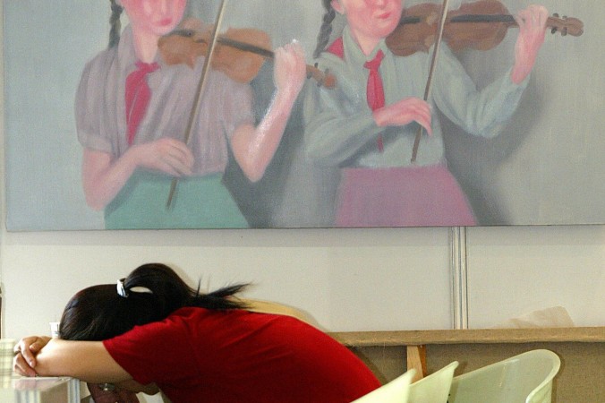 3 juin 2004 : au Salon du Printemps de l'Art à Shanghai, une femme se repose devant une peinture à l'huile représentant deux jeunes communistes (pionniers) jouant du violon. (Liu Jin/AFP/Getty Images)