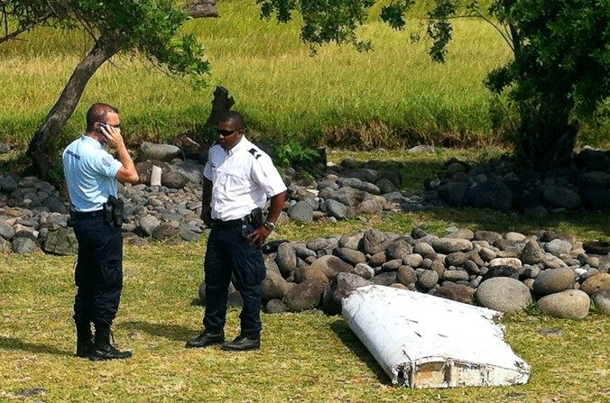 Un policier et un gendarme se tiennent à côté d'un débris d'avion encore non identifié, sur la côte de Saint-André à la Réunion, le 29 juillet 2015. (Yannick Pitou/AFP/Getty Images)
