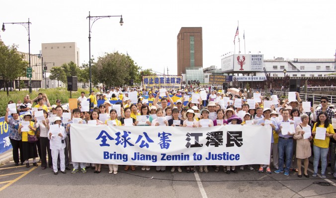 Des pratiquants de Falun Gong tiennent dans leur main leur plainte pénale contre Jiang Zemin lors d’un rassemblement devant l’ambassade chinoise à New York, le 3 juillet 2015. (Larry Dye/Epoch Times)