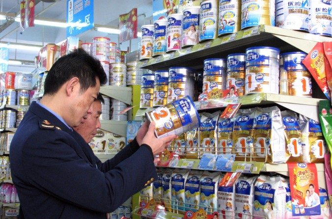 Le 9 février 2010 : des agents chinois vérifient les dates sur des boîtes de lait en poudre dans une boutique de Tongzi, province du Guizhou au sud-ouest de la Chine pour vérifier qu’il ne s’agit pas de produits contaminés à la mélamine. (AFP / Getty Images)