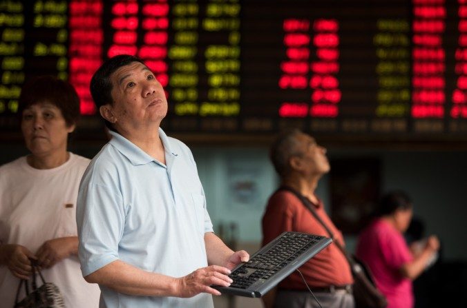 Des investisseurs surveillent les écrans montrant les cotations du marché boursier dans une maison de courtage à Shanghai le 13 août 2015. (Johannes Eisele / AFP / Getty Images)