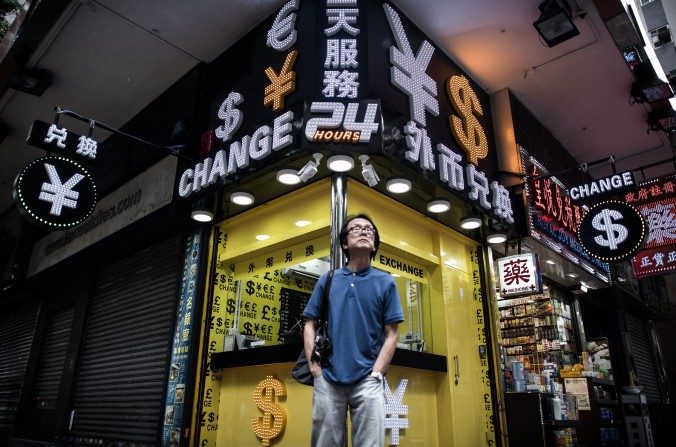 Un homme debout devant une boutique de change à Hong Kong, le 13 août 2015. (Philippe Lopez/AFP/Getty Images)