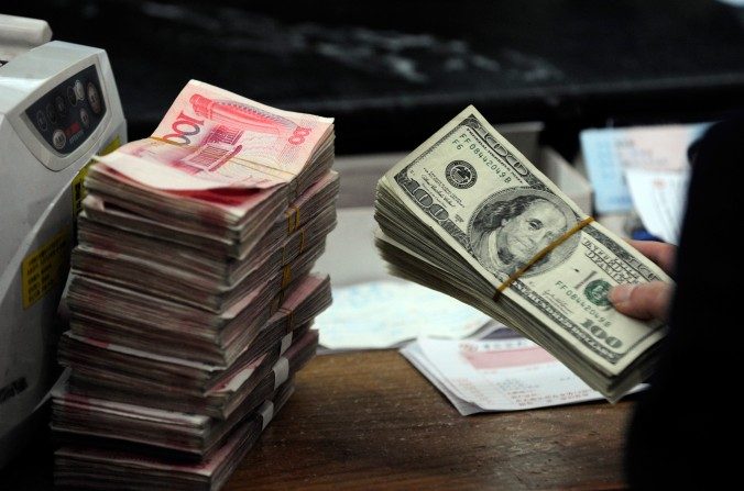 Un employé de banque chinois se prépare à compter une pile de dollars américains et une pile de yuans chinois dans une banque à Hefei, province d’Anhui.  (STR/AFP/Getty Images)