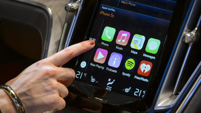 Durant une exposition Geneva Motor en Belgique en 2014, une utilisatrice interagit avec un écran Apple Car Play. Apple a fait savoir que de nombreuses fonctionnalités présentes sur iPhone, dont l'usage de Siri seraient installées sur leur système. (FABRICE COFFRINI/AFP/Getty Images)