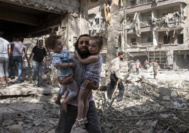 Un homme syrien porte ses deux filles à travers les décombres, après une attaque du régime syrien au baril de TNT sur un quartier tenu par les rebelles d'al-Kalasa dans la ville d'Alep, dans le nord de la Syrie, le 17 septembre 2015. Le régime chinois est en train de fournir des armes au régime d'Assad à travers l'Iran. (Karam al-Masri / AFP / Getty Images)
