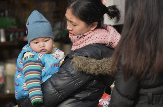 Une mère porte son enfant dans une rue de Shanghai. (Peter Parks/AFP/Getty Images)