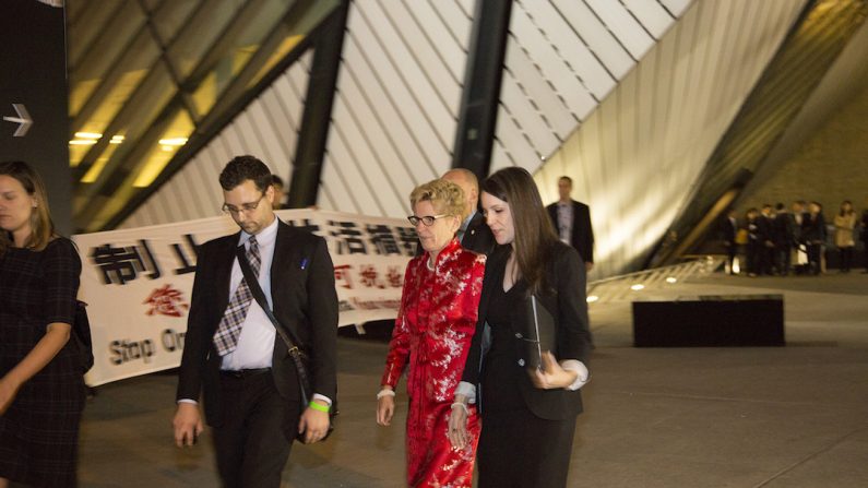 La première ministre de l’Ontario, Kathleen Wynne, passe à côté de manifestants dénonçant la présence du responsable chinois Luo Zhijun, accusé de graves violations des droits de la personne. Mme Wynne a rencontré M. Luo à Toronto le 7 octobre 2015 et a bloqué l’accès aux médias. (Epoch Times)