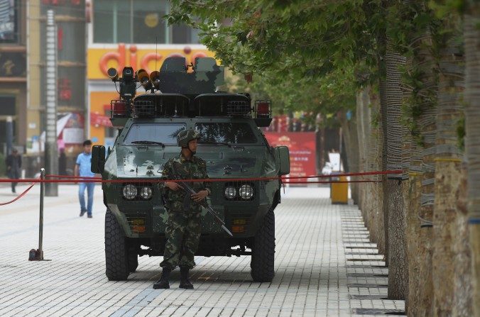 Un policier paramilitaire chinois monte la garde devant un véhicule blindé à Hotan, dans le Xinjiang, en Chine. Le régime chinois a intensifié sa répression de l'ethnie ouïghoure dans la région. (Greg Baker/AFP/Getty Images)