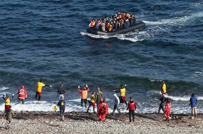 Les travailleurs humanitaires font des signes à un bateau de migrants qui, après la traversée en provenance de Turquie, accoste sur l'île grecque de Lesbos le 17 novembre 2015, à Sikaminias en Grèce (Carl Court/Getty Images)