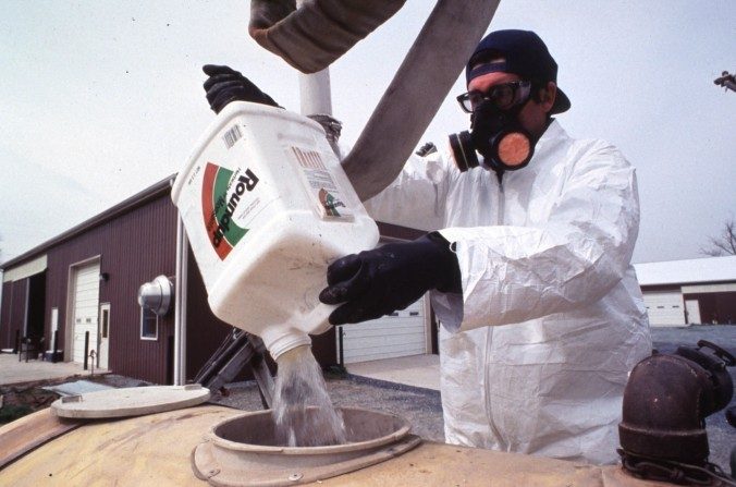 Un agriculteur verse l'herbicide RoundUp de Monsanto dans un réservoir. (USDA)