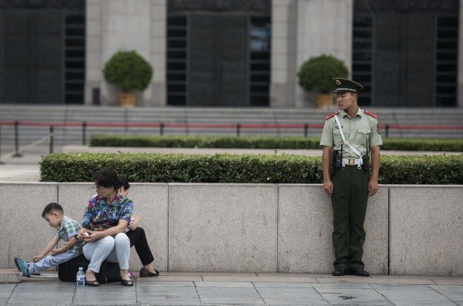 Un policier paramilitaire surveille une famille sur la place Tiananmen à Pékin, le 1er septembre 2015. (Fred Dufour / AFP / Getty Images)