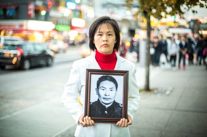 Jiang Li avec une photo de son défunt père, Jiang Xiqing, à Flushing, dans le Queens, le 1er novembre 2015. Son père mort dans un camp de travail forcé en Chine après avoir été persécuté par les autorités communistes pour la pratique de la discipline spirituelle Falun Gong. (Benjamin Chasteen / Epoch Times)