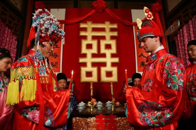 Un couple de jeunes mariés, l'époux français et la mariée chinoise, lors d'une cérémonie chinoise au Jardin de la grande vue à Pékin, le 5 mai 2007. (China Photos / Getty Images)
