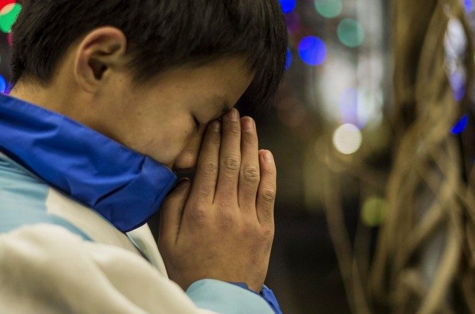 Un jeune croyant chinois prie lors de la messe la veille de Noël dans une église catholique à Pékin le 24 décembre 2014. (Fred Dufour / AFP / Getty Images)