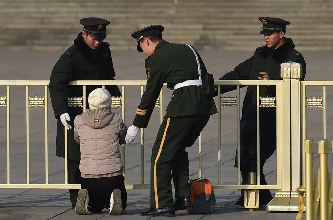 La police paramilitaire arrête une femme qui proteste à genoux devant le Grand palais du peuple à Pékin, le 13 mars 2015. (GREG BAKER / AFP / Getty Images)