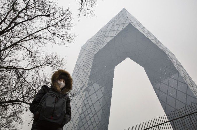 Une Chinoise porte un masque pour se protéger contre la pollution près du bâtiment de la Télévision centrale de Chine (CCTV), le 8 décembre 2015 à Pékin. (Kevin Frayer / Getty Images)