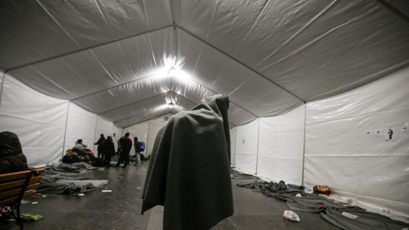 Une couverture sur le sac à dos, un réfugié lutte contre le froid dans une tente chauffée du camp de transit d’Idomeni. (Dimitrios Tosidis, Idomeni, Grèce)