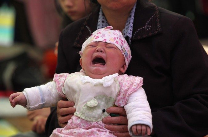 Cette photo prise le 23 avril 2013 montre Li Jie âgée de 4 mois qui pleure dans les bras de sa mère dans un logement temporaire à l’agglomération de Lingguan, canton de Baoxing à Yaan, province du Sichuan dans le sud-ouest de la Chine. (AFP / AFP / Getty Images)