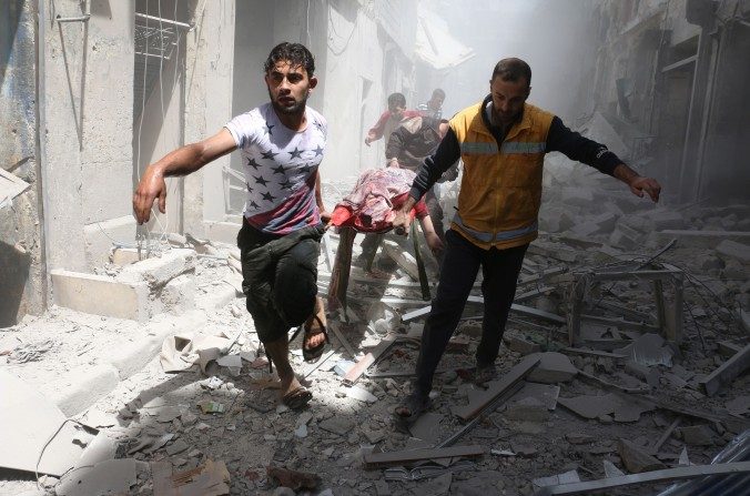 Des Syriens transportent un corps sur un brancard au milieu des décombres des bâtiments détruits par un raid aérien visant Al-Qatarji, située dans la ville d’Alep, au nord de la Syrie. La zone bombardée le 29 avril serait sous contrôle des rebelles. (Ameer Alhalbi/AFP/Getty Images)