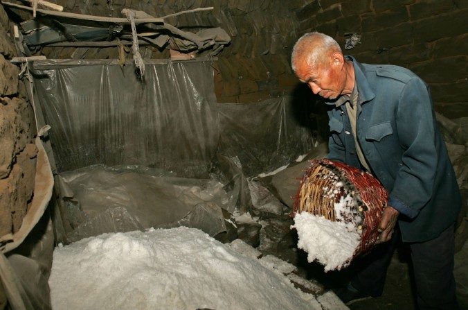 Un ouvrier chinois rajoute du sel à un tas au village de Lijiawa dans le canton de Zizhou, province du Shaanxi, le 31 mars 2006. (Chine Photos / Getty Images)