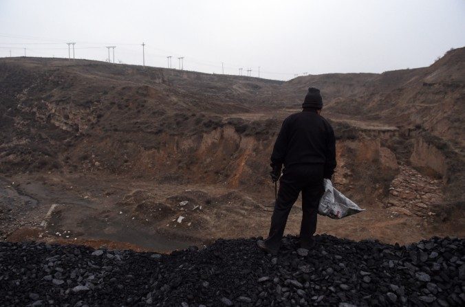 Une Chinoise debout sur un tas de charbon à proximité d'une mine de charbon à Datong dans la province du Shanxi, le 20 novembre 2015. Le charbon est l'un des secteurs difficile à réformer. (Greg Baker / AFP / Getty Images)