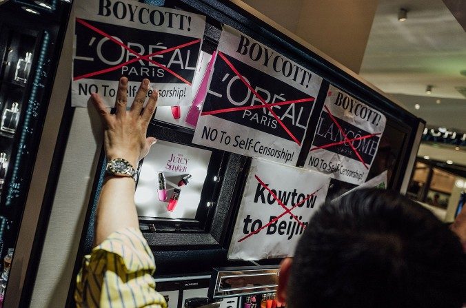 Des manifestants collent des affiches et crient des slogans lors du rassemblement contre la marque française de produits cosmétiques Lancôme en face de la boutique de Lancôme à Causeway Bay, Hong Kong, le 8 juin 2016. (Anthony Kwan / Getty Images)