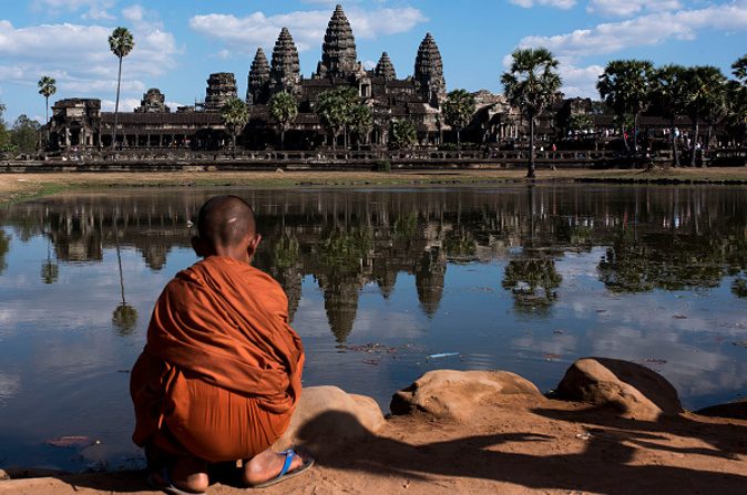 Un jeune moine assis devant le temple d’Angkor Vat, le 1er janvier 2016, à Siem Riep au Cambodge. Angkor était la capitale de l’Empire Khmer, approximativement entre le 9e et le 15e siècle. (Xaume Olleros/Getty Images)