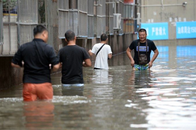 Des gens traversant la zone inondée dans le district de Changping à Pékin, le 21 juillet 2016. Des pluies torrentielles dans le nord de la Chine ont récemment causé la mort de 130 personnes dans la province alentour de Pékin. (STR / AFP / Getty Images)