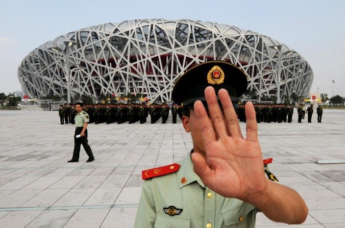 Un agent de la police paramilitaire chinoise essaye d’interrompre la prise de photos lors de la répétition du défilé militaire avant les Jeux Olympiques de Pékin de 2008. (Mark Ralston / AFP / Getty Images)