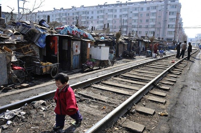 Un enfant joue sur les rails du chemin de fer dans un bidonville d’appartements à loyer modéré, construits par le gouvernement à Shenyang dans la province du Liaoning, le 11 mars 2009. (Chine Photos / Getty Images)