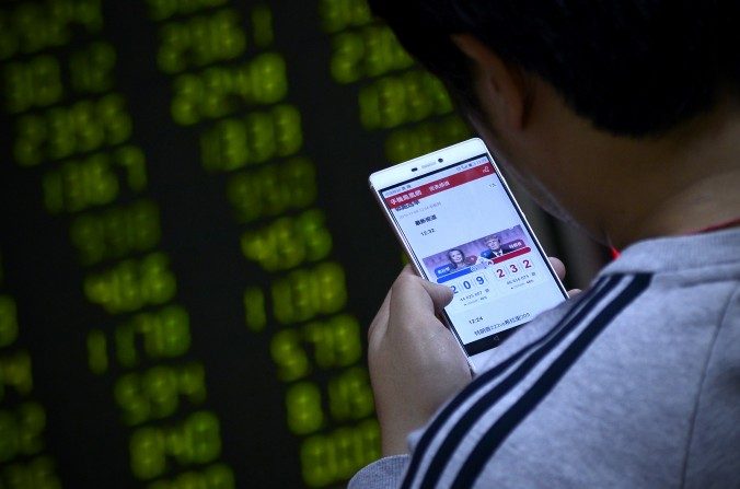 Un investisseur chinois d'une société anonyme suit l'élection présidentielle américaine sur son smartphone, à Pékin le 9 novembre 2016 (WANG ZHAO/AFP/Getty Images)